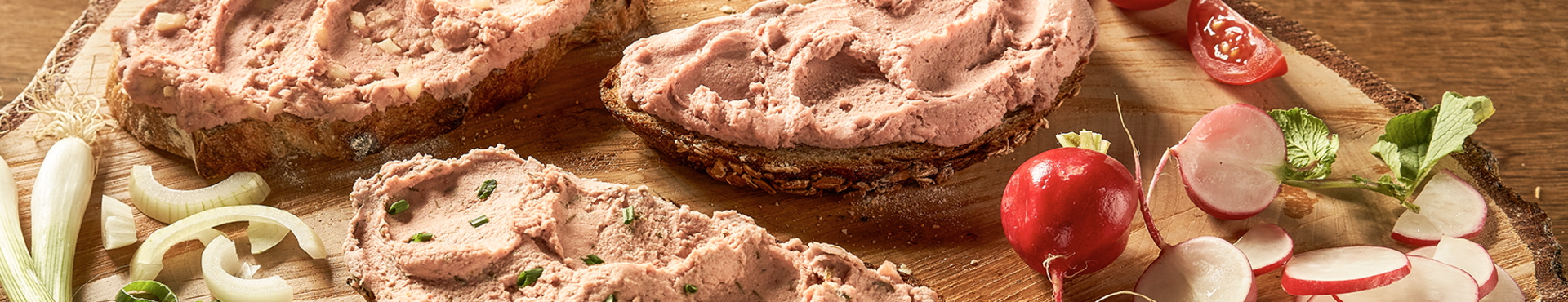 Rügenwalder Mühle vegane Pommersche Titelbild: Reich mit veganer Pommerschen geschmierte Stullen auf rustikalem Holzbrett